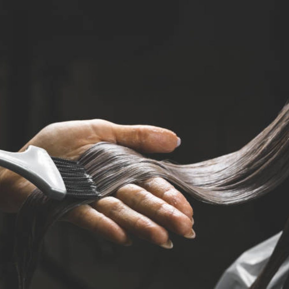 Close up of colorist dyes hair of woman with brush and foil in beauty salon