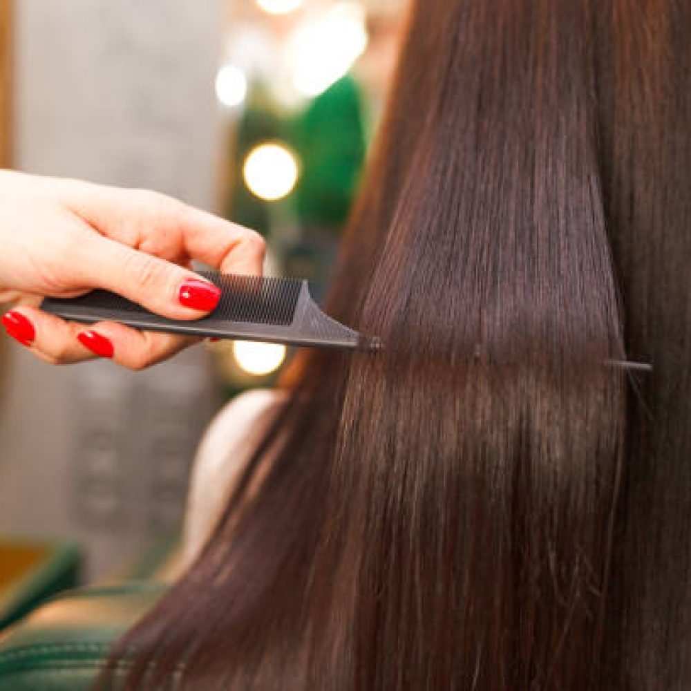 Straight and shiny hair after lamination. Hairdresser demonstrates the result of keratin hair straightening