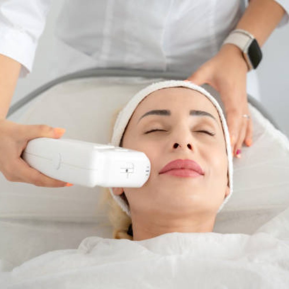Woman getting laser facial lifting therapy in beauty salon